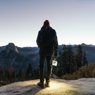 Pessoa vestindo roupa de inverno com lanterna ao ar livre ao pôr do sol.