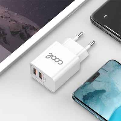 Carregador USB branco com plugue europeu e dois conectores laranja ao lado de smartphones