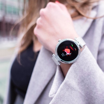 Relógio inteligente prateado com bracelete metálica num pulso feminino