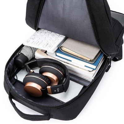 Mochila preta aberta com headphones, cadernos e teclado branco no interior