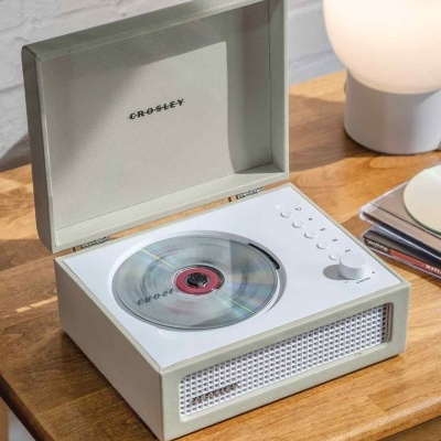 Leitor de CD branco CROSLEY com caixa aberta em cima de mesa de madeira.