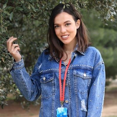 Mulher de casaco de ganga azul com cordão vermelho e cartão com fundo azul e branco, ao ar livre