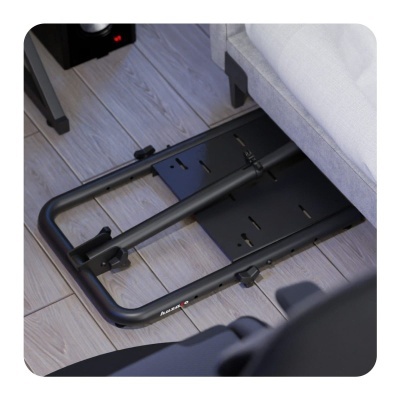 Suporte metálico preto colocado debaixo de sofá cinzento claro sobre chão de madeira.