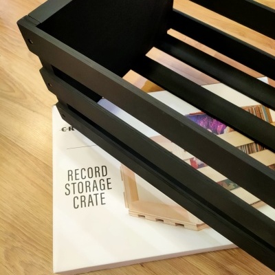 Caixa de armazenamento para discos em madeira preta sobre caixa branca com texto