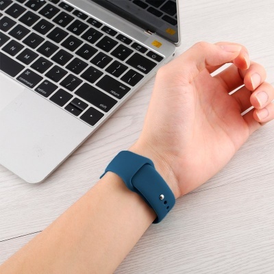 Pulseira de relógio azul em pulso junto a computador portátil