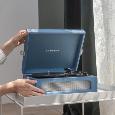 Gira-discos portátil azul CROSLEY numa mesa branca perto de uma janela com cortinas
