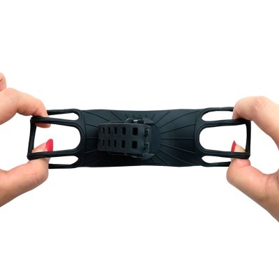 Dispositivo elástico preto com fivela e duas extremidades em formato de laço, segurado por duas mãos com unhas vermelhas, sobre fundo branco