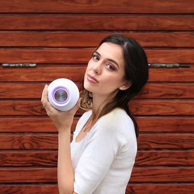 Mulher segurando objeto redondo branco com círculo roxo e cinza em frente a porta de madeira