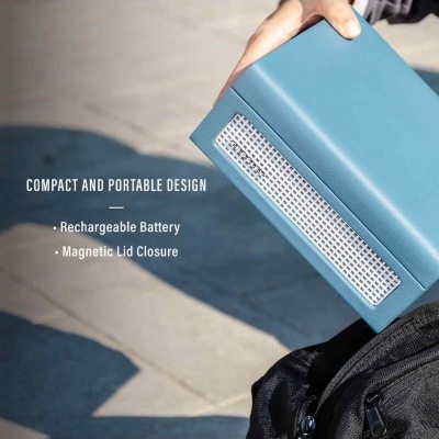 Caixa portátil azul com grelha branca junto a mochila preta