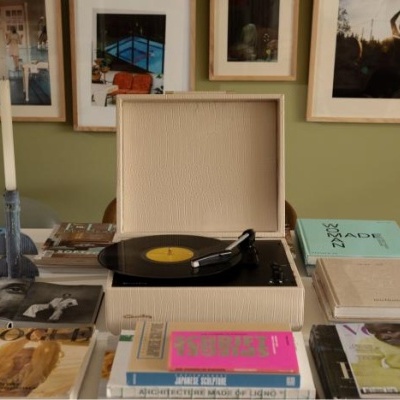 Gira-discos bege com vinil a tocar e livros numa mesa