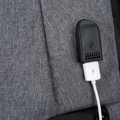 Porta USB preta ligada a cabo branco numa mochila cinza