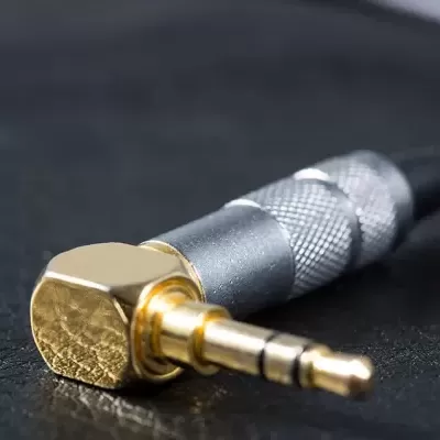 Cabo áudio com ficha jack 3,5 mm dourada em metal e cabo preto em superfície preta