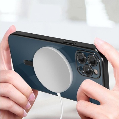 Smartphone preto com carregador magnético branco ligado na parte traseira, segurado por duas mãos.