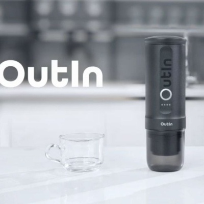 Frasco preto Outln ao lado de chávena de vidro num balcão