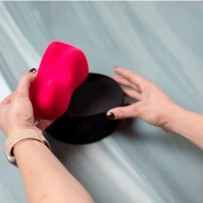 Mãos segurando esponja vermelha e recipiente preto sobre superfície azul claro