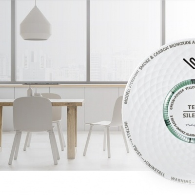 Detector de fumo branco redondo com botão de teste e silêncio sobre fundo de cozinha e sala de jantar minimalista