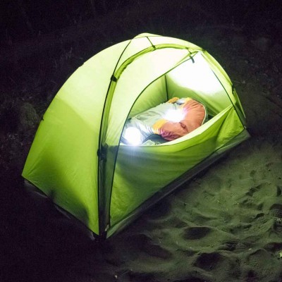 Tenda de campismo verde com uma pessoa dentro numa noite