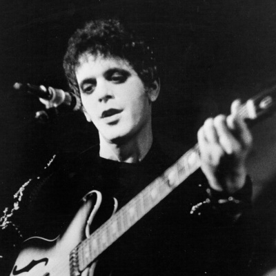 Homem a tocar guitarra elétrica em palco com microfone