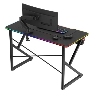 Secretária de jogos preta com luzes LED coloridas no tampo, suporte de monitor, teclado e comandos de jogos.