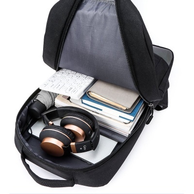 Mochila preta aberta com auscultadores, teclado, livros e guarda-chuva dentro