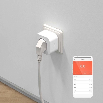 Tomada elétrica branca com adaptador e cabo ligados na parede, chão de madeira clara, e telemóvel com app de monitorização de energia.