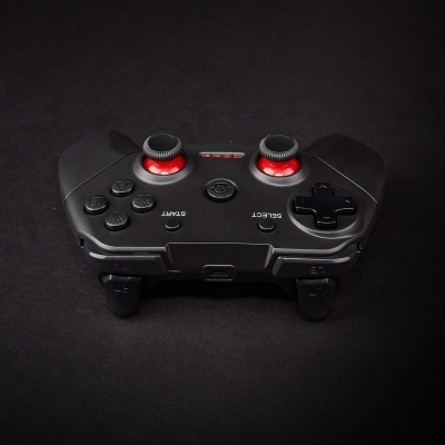 Comando de videojogo preto com botões e joysticks encarnados.