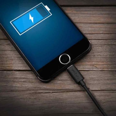 Smartphone preto com ícone de bateria a carregar numa superfície de madeira