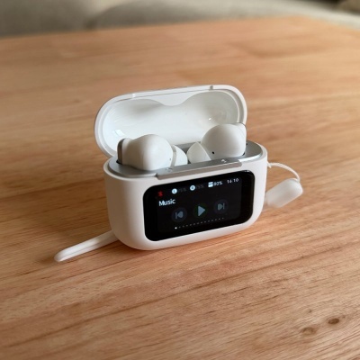 Estojo branco aberto com auriculares ecrã digital interface de música sobre madeira