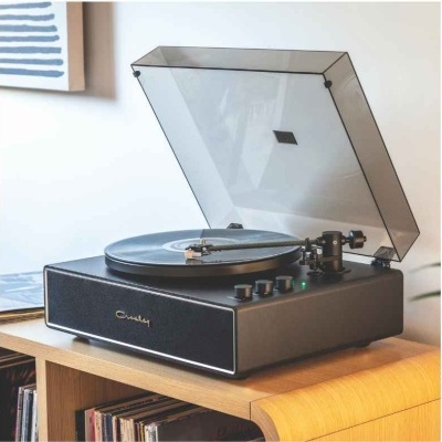 Gira-discos preto com tampa transparente sobre mesa de madeira