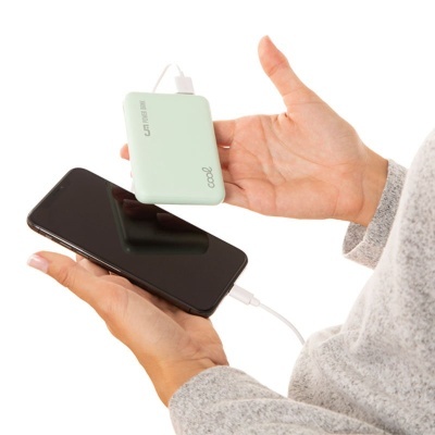 Power bank verde clara carregando smartphone preto nas mãos de pessoa com camisola cinzenta