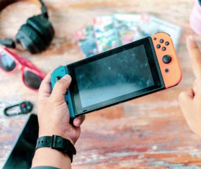 Consola Nintendo Switch com comandos azul e vermelho numa mesa de madeira