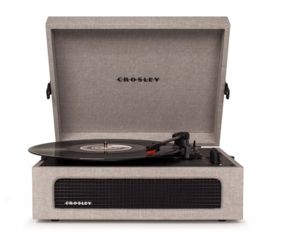Gira-discos Crosley bege com tampa aberta e vinil a tocar.