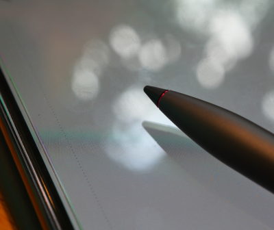 Caneta digital preta com ponta vermelha sobre ecrã de tablet