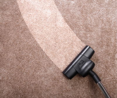 Aspirador de pó preto a aspirar tapete bege e castanho claro