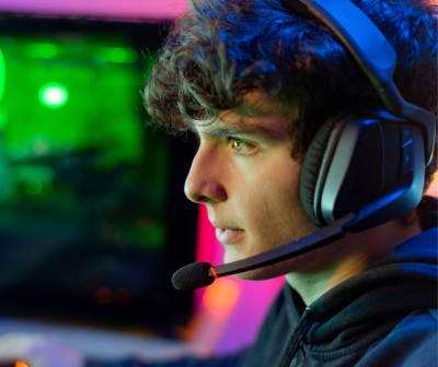 Headset gaming preto com microfone usado por jovem com iluminação LED colorida ao fundo