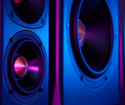 Altifalantes pretos com cones metálicos rosas iluminados por luzes azuis