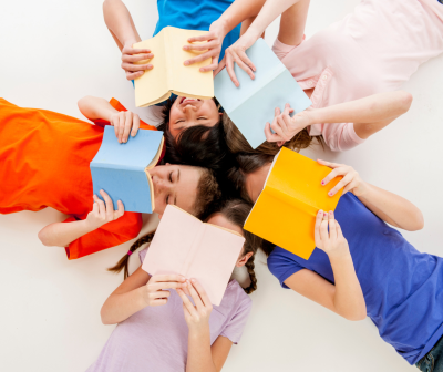 Crianças deitadas em círculo segurando livros coloridos