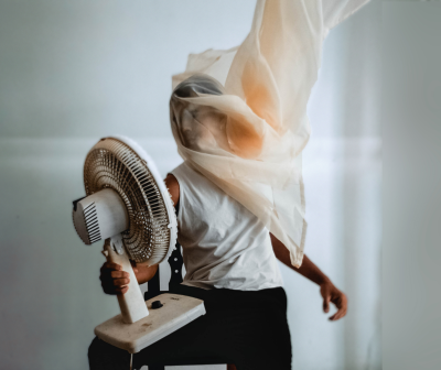 Ventoinha branca de pé com detalhes pretos segurada por pessoa com tecido translúcido esvoaçando