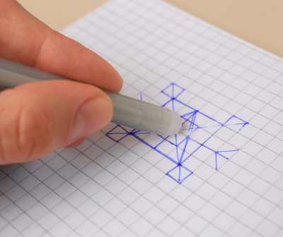 Mão a apagar desenho a tinta azul em caderno quadriculado