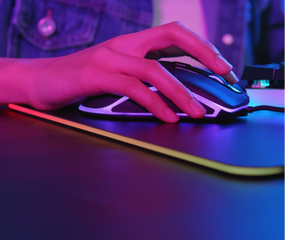 Rato de computador preto com detalhes em branco numa mão sobre um tapete de rato iluminado