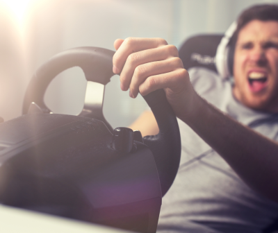 Homem a segurar volante de jogo preto com suporte, expressão animada, usando auscultadores