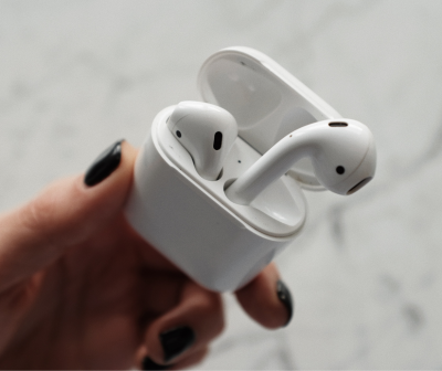 Auriculares sem fios brancos dentro de estojo de carregamento branco na mão de uma pessoa