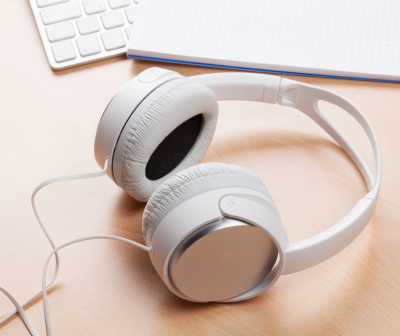 Headphones brancos com almofadas almofadadas em tecido preto sobre mesa de madeira clara