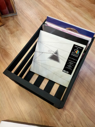 Caixa preta de armazenamento com discos de vinil em chão de madeira