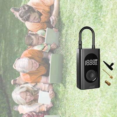 Bomba elétrica portátil preta com visor digital e adaptadores sobre relva, pessoas a lerem tablets no fundo