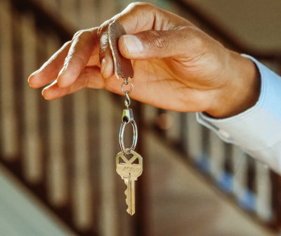 Mão segurando chave branca com chaveiro de pele castanha claro