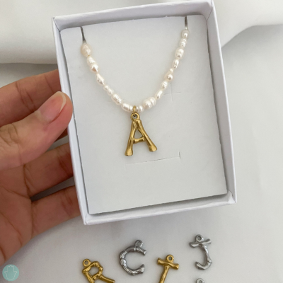 Colar de pérolas com pendente letra A dourado em caixa branca com pendentes letras dourado e prateado