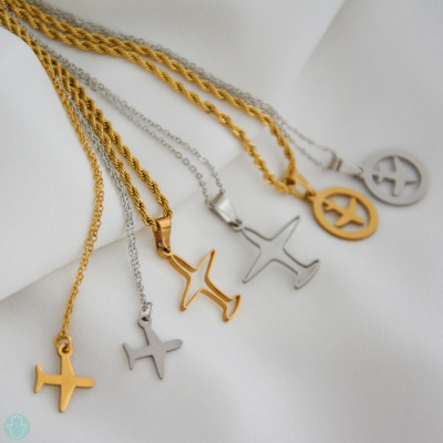 Conjunto de cinco colares com pendentes de avião em dourado e prateado sobre tecido branco