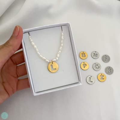 Colar com pérolas e pendente de letra L dourado com discos de letras extras ao lado