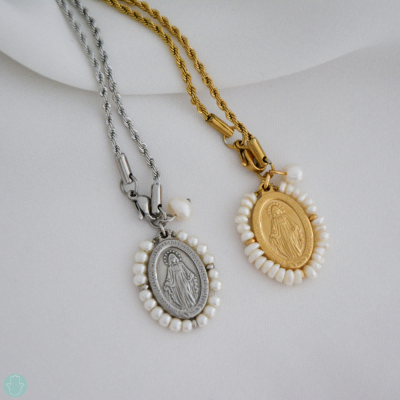 Dois colares com medalhões ovais prateado e dourado com pérolas brancas sobre tecido branco